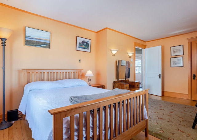 bedroom with crown molding, baseboards, and wood finished floors