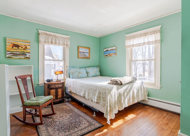 bedroom with crown molding, hardwood / wood-style floors, and baseboard heating