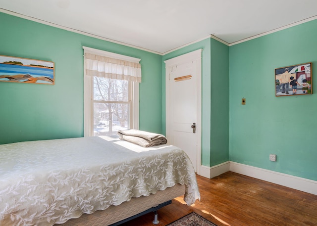 bedroom featuring ornamental molding, baseboards, and wood finished floors