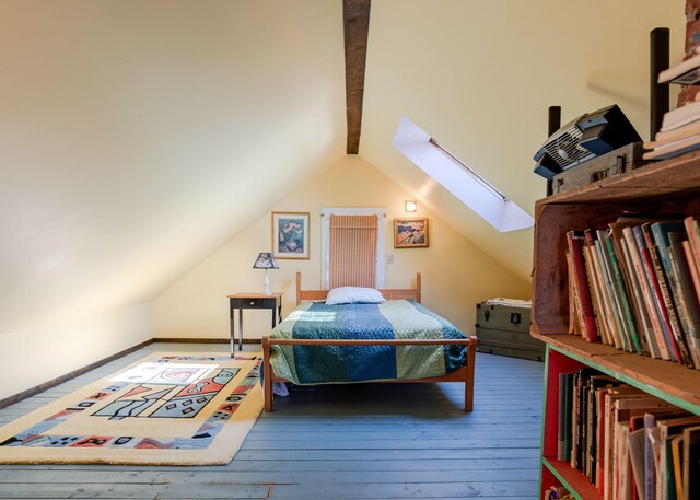 bedroom featuring vaulted ceiling with skylight, wood-type flooring, and baseboards