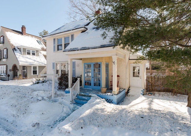 view of front of home featuring stucco siding, fence, and french doors