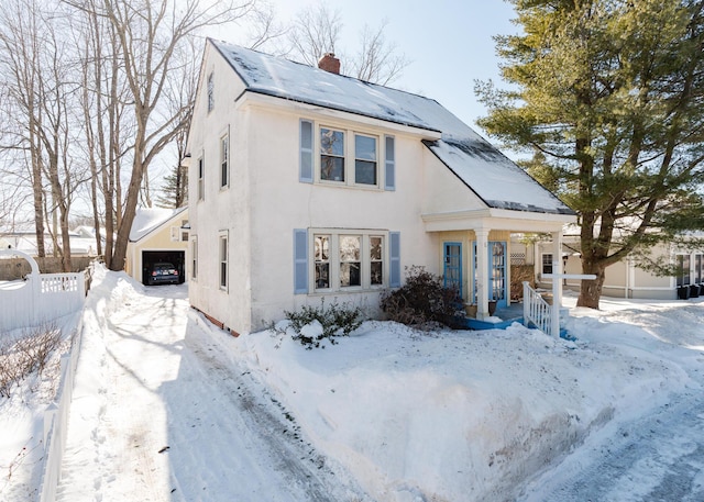 view of front of house featuring a chimney, roof mounted solar panels, fence, and stucco siding