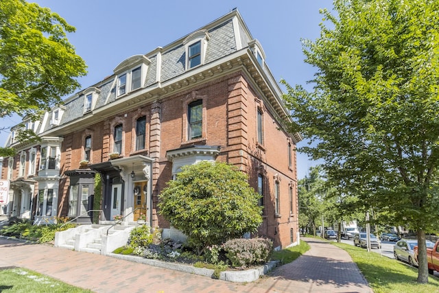 view of front of house with mansard roof and brick siding