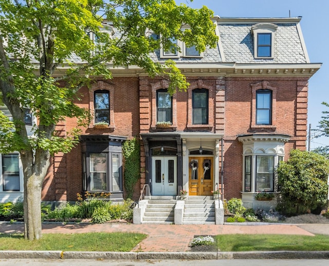 victorian home featuring a high end roof, mansard roof, and brick siding