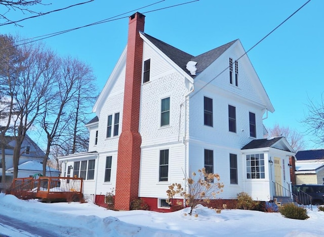 view of snow covered exterior featuring a chimney and a wooden deck