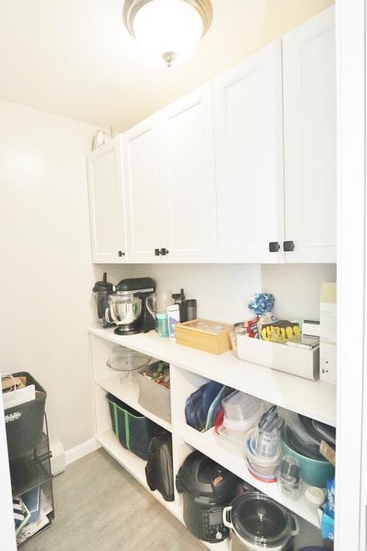 interior space featuring light wood-style flooring, baseboards, white cabinets, and light countertops