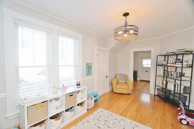 rec room featuring a chandelier, ornamental molding, and wood finished floors