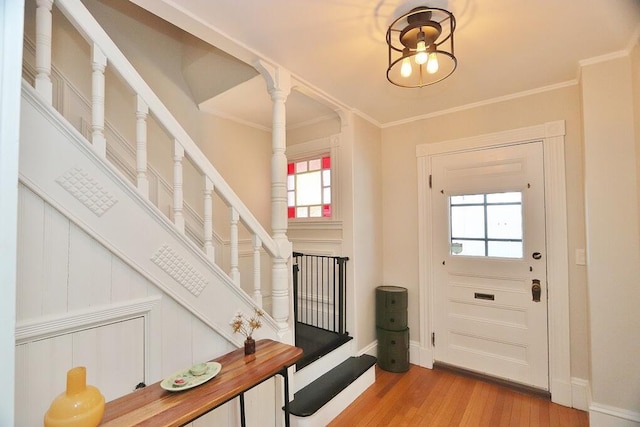 doorway with ornate columns, ornamental molding, wood finished floors, and baseboards