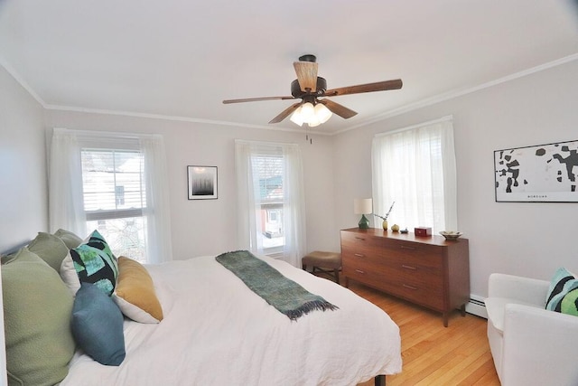 bedroom featuring light wood-type flooring, multiple windows, baseboard heating, and crown molding