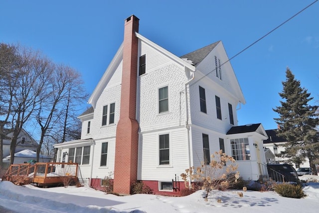 view of snowy exterior with a deck and a chimney