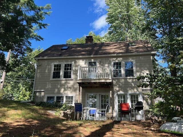 back of property with a chimney and a balcony