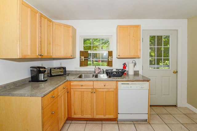 kitchen featuring dark countertops, dishwasher, a sink, and light tile patterned floors