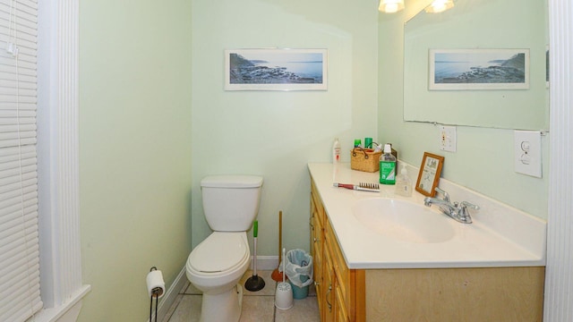 bathroom with toilet, baseboards, vanity, and tile patterned floors