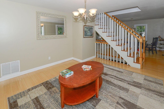 living room with baseboards, visible vents, stairway, wood finished floors, and an inviting chandelier