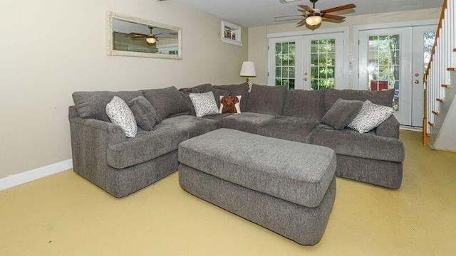 living room with a ceiling fan, french doors, baseboards, and stairs