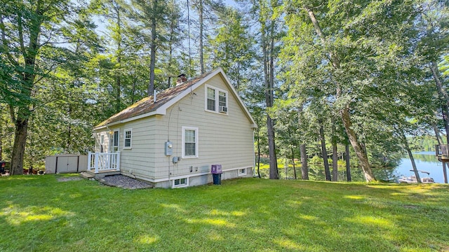 view of home's exterior with a water view, a yard, an outdoor structure, and a shed