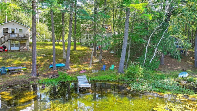 view of yard featuring stairway and a deck with water view