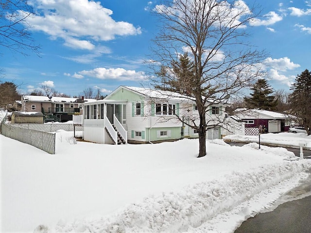 view of front of property featuring a garage, a sunroom, and fence