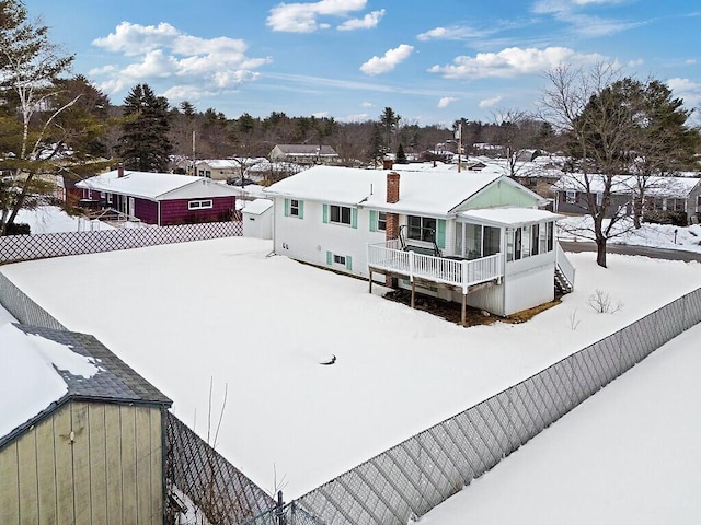 snow covered rear of property featuring a chimney and fence