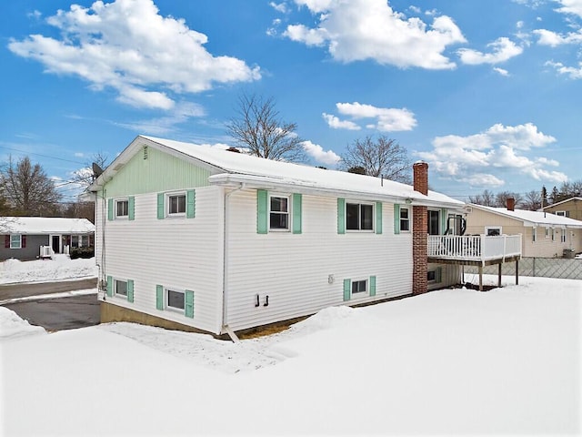 snow covered rear of property with a chimney