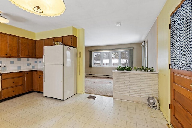 kitchen featuring light countertops, visible vents, backsplash, baseboard heating, and freestanding refrigerator