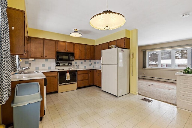 kitchen featuring range with electric stovetop, a baseboard radiator, freestanding refrigerator, a sink, and black microwave