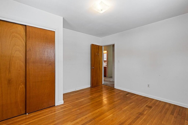 unfurnished bedroom with a closet, baseboards, and hardwood / wood-style floors