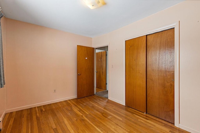 unfurnished bedroom featuring a closet, baseboards, and hardwood / wood-style flooring