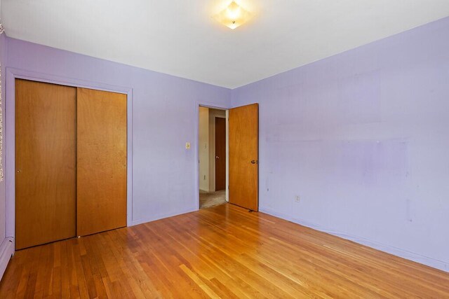 unfurnished bedroom with light wood-style floors, a closet, and baseboards