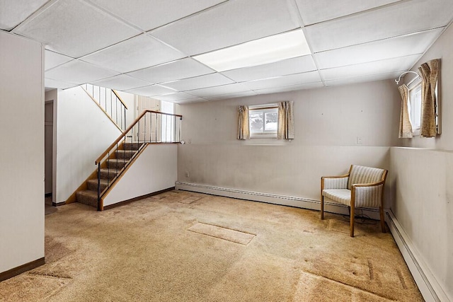 below grade area featuring a baseboard radiator, stairway, carpet flooring, a drop ceiling, and baseboards