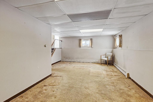 basement with carpet floors, a paneled ceiling, and baseboards