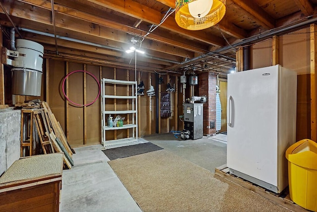 unfinished basement with a heating unit and freestanding refrigerator