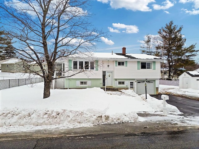 view of front facade featuring a garage, a chimney, fence, and driveway