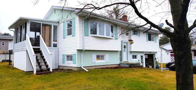 rear view of house featuring a sunroom, a yard, and a chimney