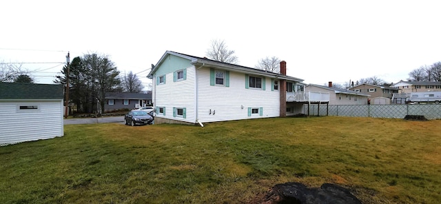 back of house featuring a residential view, a lawn, a chimney, and fence