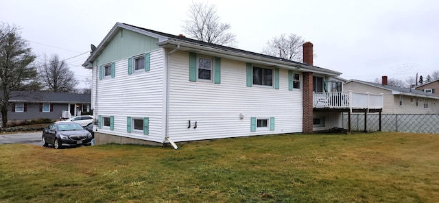 rear view of house with a lawn, a chimney, and fence