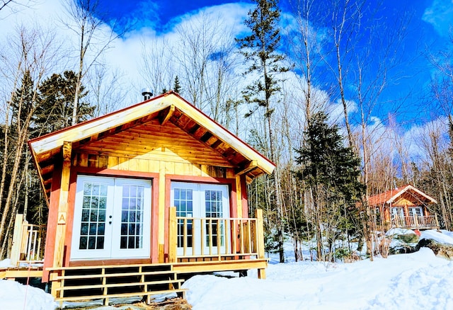 snow covered structure with an outbuilding and french doors