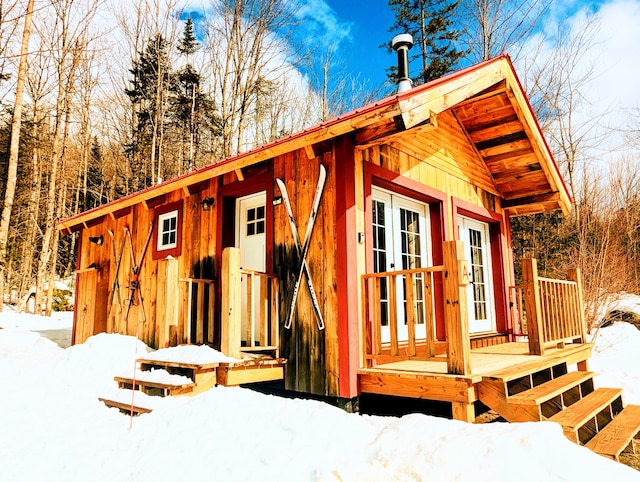 snow covered structure featuring an outbuilding