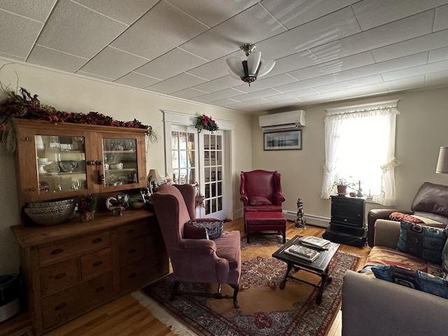 living area with a baseboard heating unit, an AC wall unit, and wood finished floors