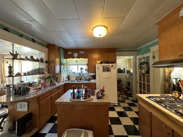 kitchen with light countertops, dark floors, freestanding refrigerator, and a center island