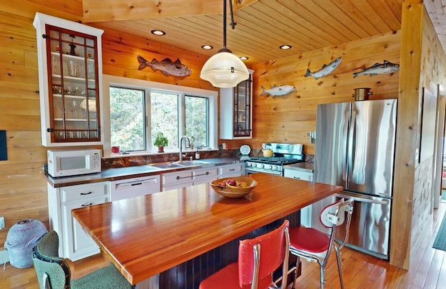 kitchen with stainless steel appliances, decorative light fixtures, glass insert cabinets, and a center island