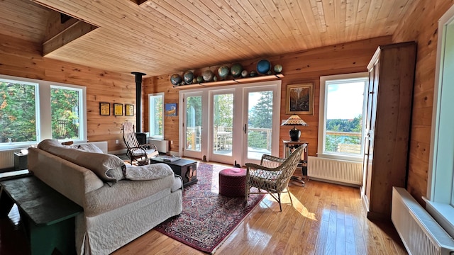 living room with a wood stove, light wood finished floors, radiator heating unit, and wood ceiling