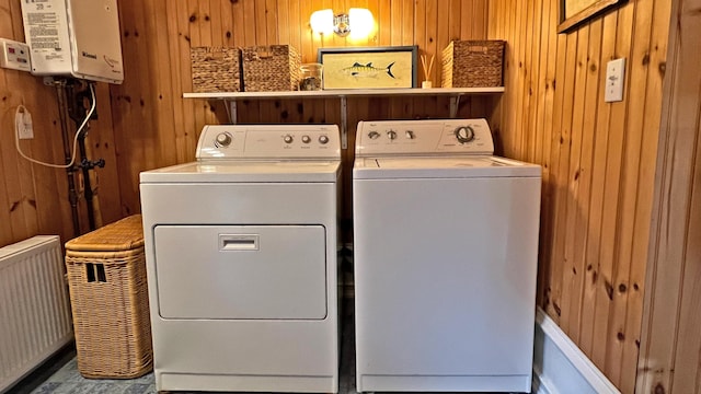 laundry room with washer and dryer, laundry area, tankless water heater, and wood walls