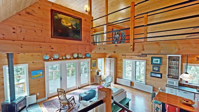 living area featuring a towering ceiling, plenty of natural light, wooden walls, and radiator