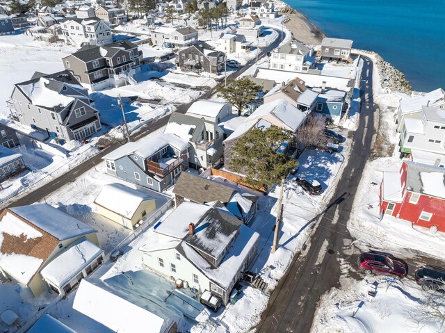 snowy aerial view featuring a water view and a residential view