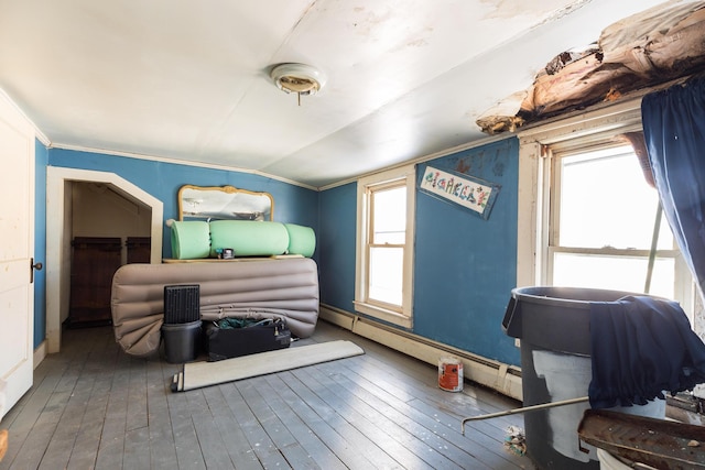 bedroom with dark wood-type flooring, a baseboard radiator, multiple windows, and vaulted ceiling