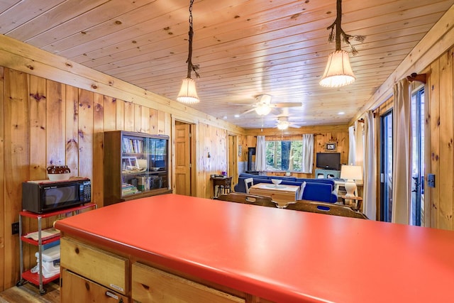 kitchen featuring wooden ceiling, wooden walls, decorative light fixtures, and black microwave