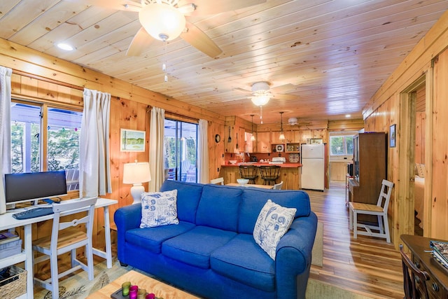 living room with wooden ceiling, light wood-style floors, ceiling fan, and wooden walls