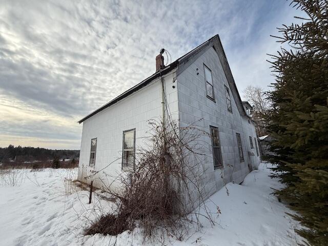 snow covered property with a chimney