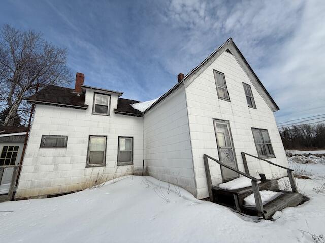 snow covered house featuring a chimney